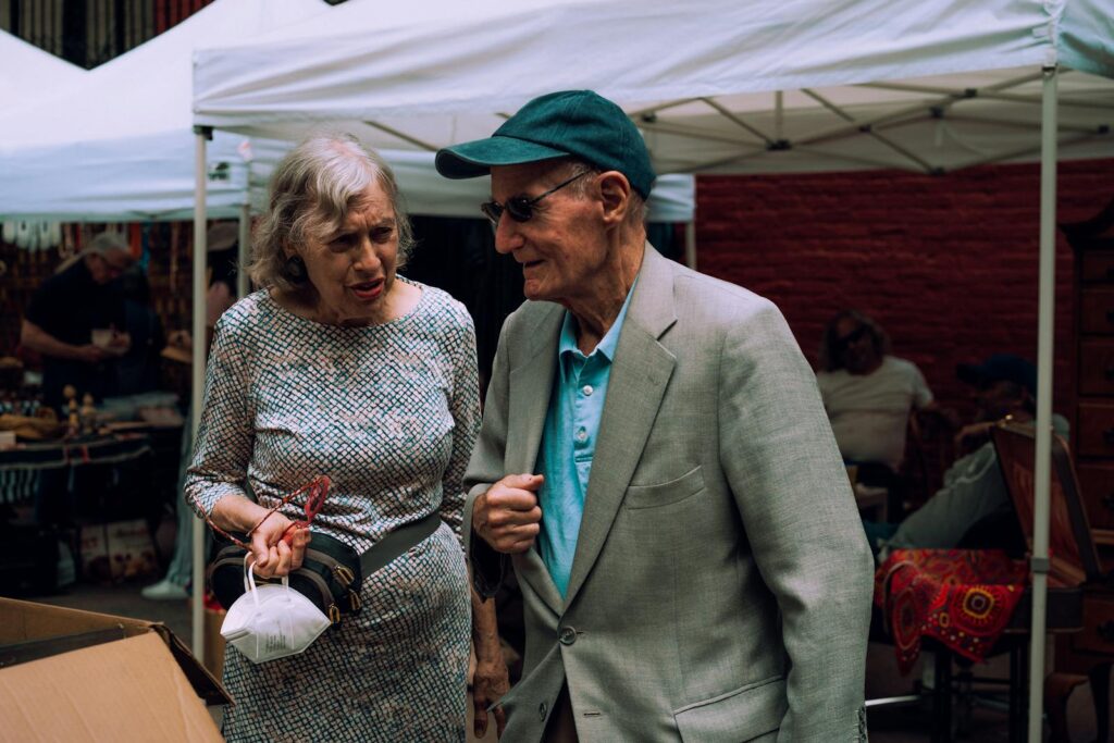 Senior couple visiting an outdoor market, enjoying a lively street atmosphere.